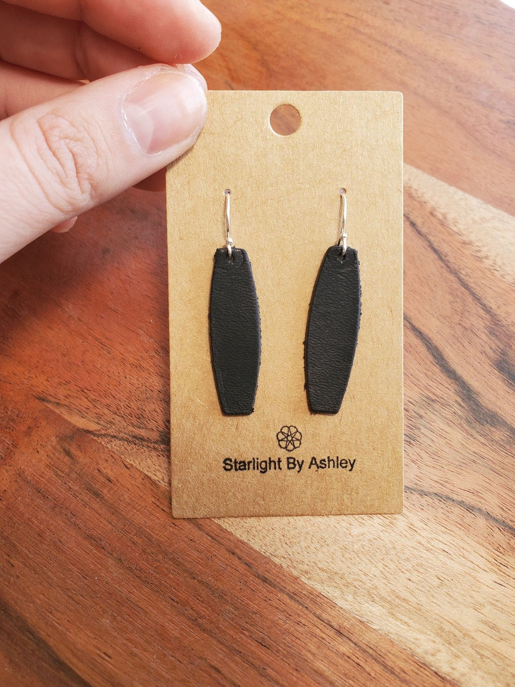 Black leather earrings with long drop teardrop shapes on metal hooks
