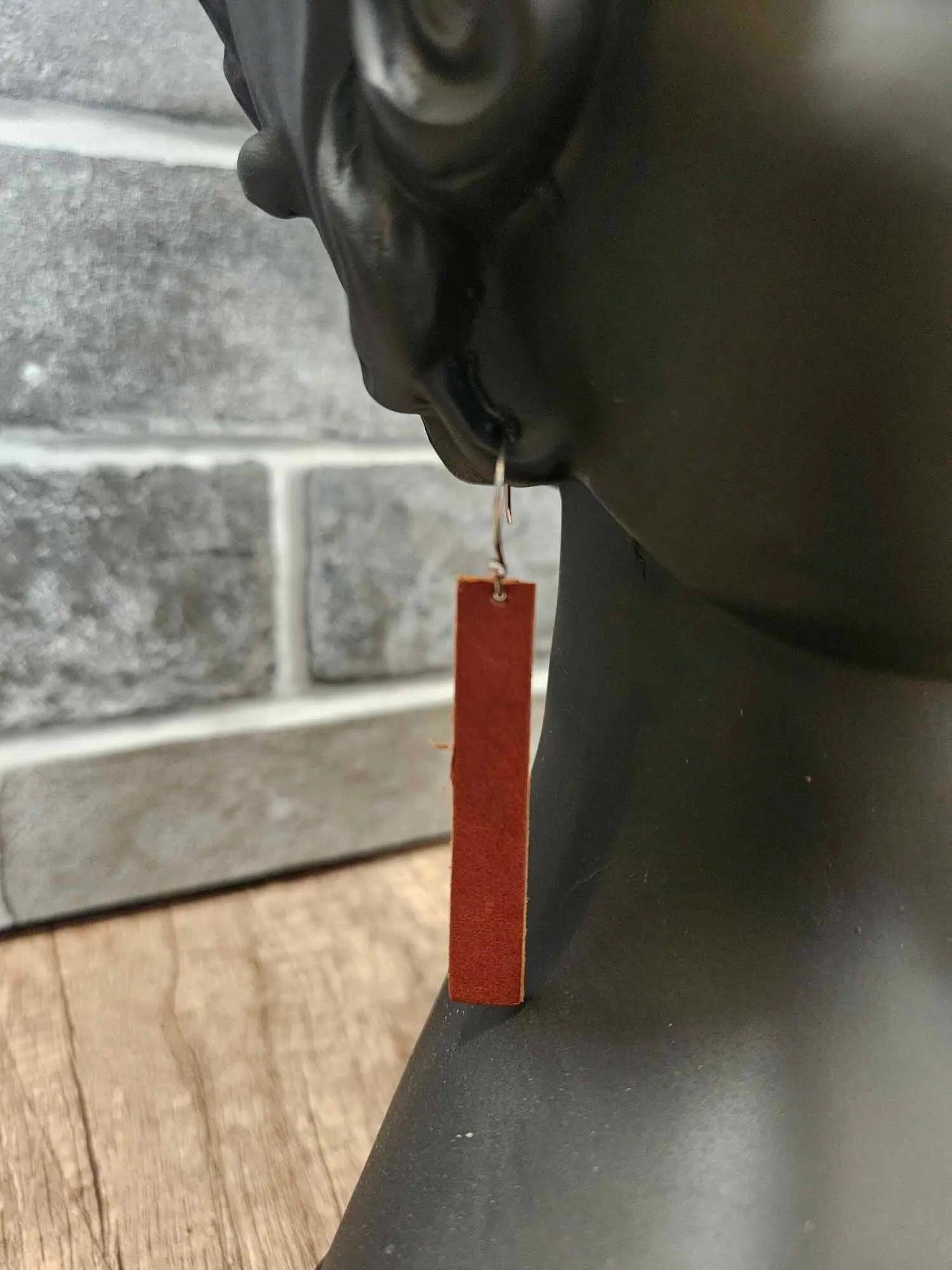 Brown leather rectangle drop earring with silver hook, shown in profile