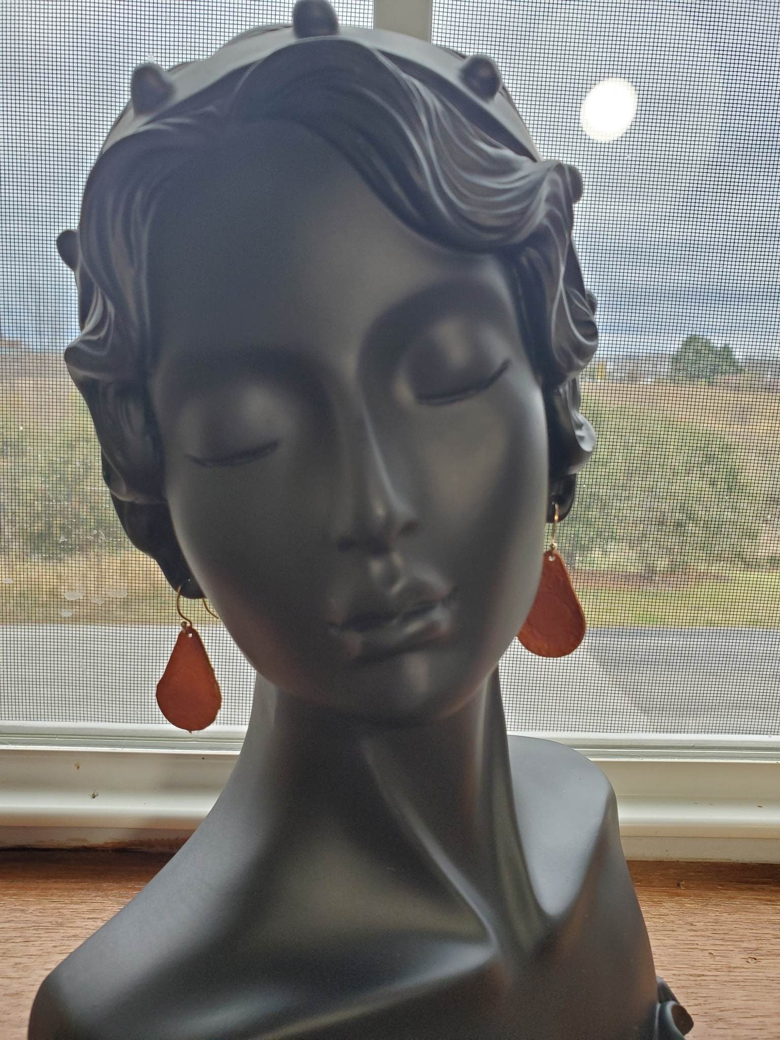 Rust red teardrop leather earrings with silver hook on model