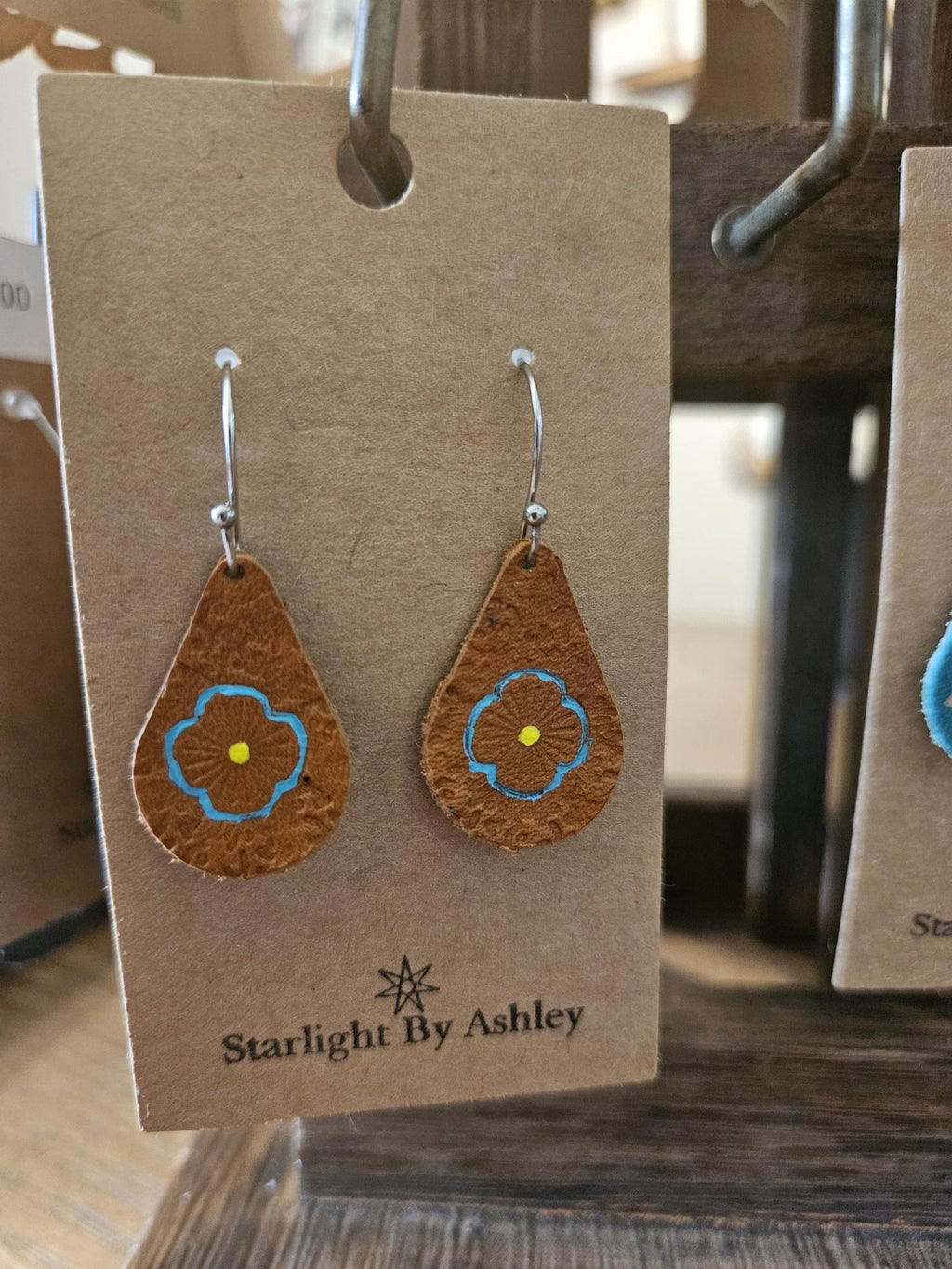 Brown leather teardrop flower earrings with blue painted centers and silver hooks