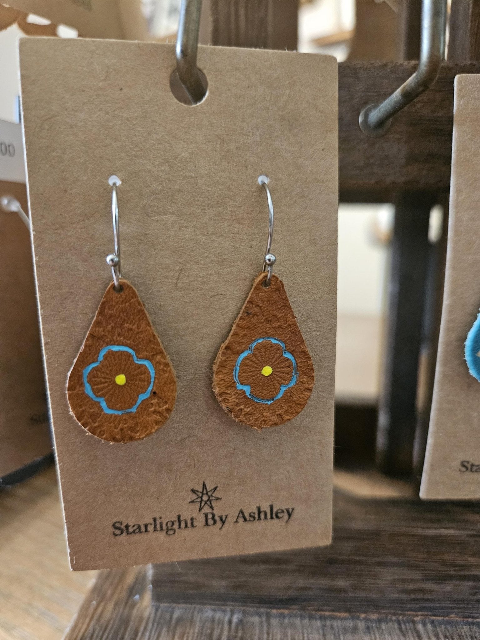 Brown leather teardrop flower earrings with blue painted centers and silver hooks