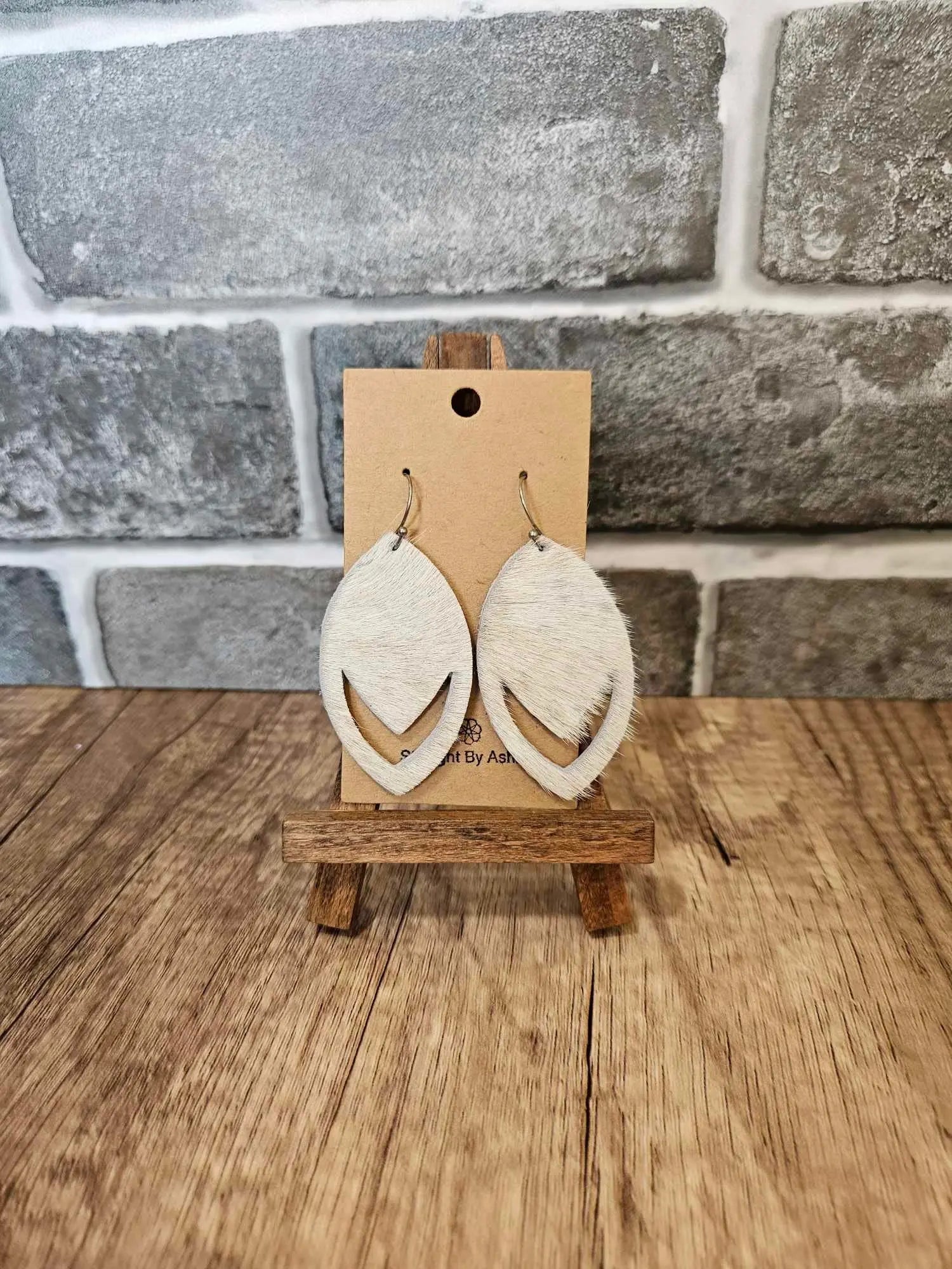 Pair of hair-on-hide leather teardrop earrings with tan fur and curved edges