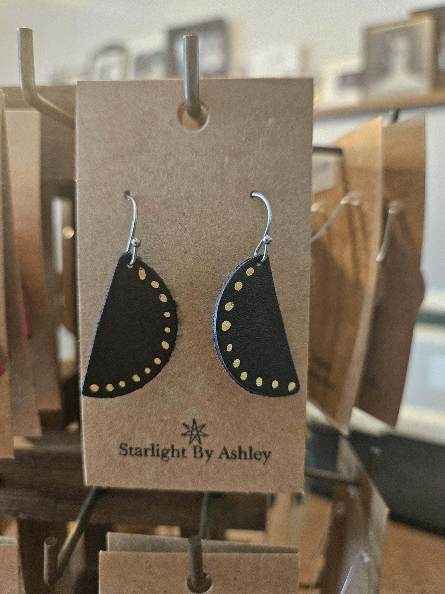Black half-circle leather earrings with yellow-studded edge and silver hooks