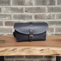 Black leather dopp bag with top flap and brass buckle, front view