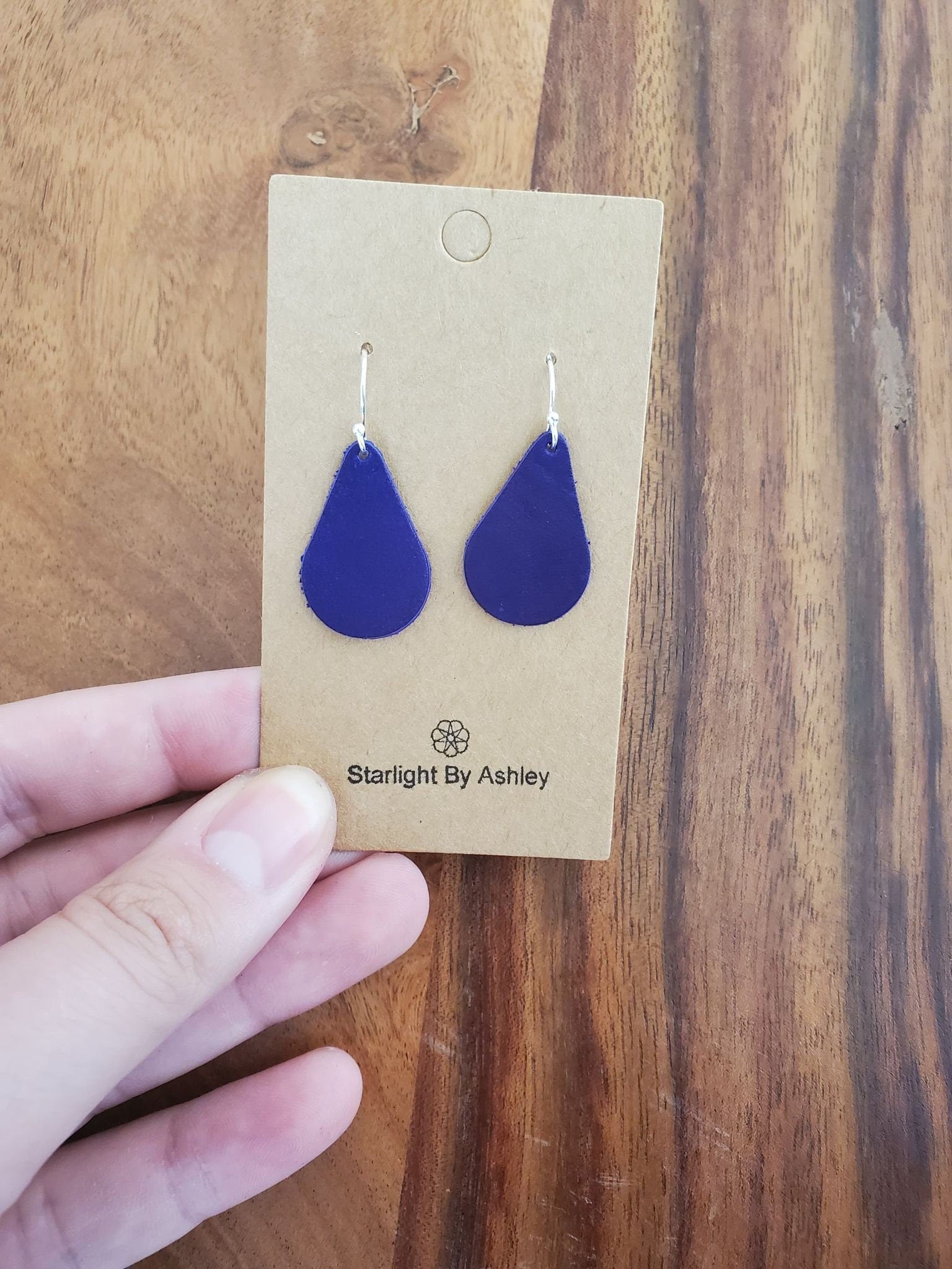Purple teardrop leather earrings on display card with silver hooks