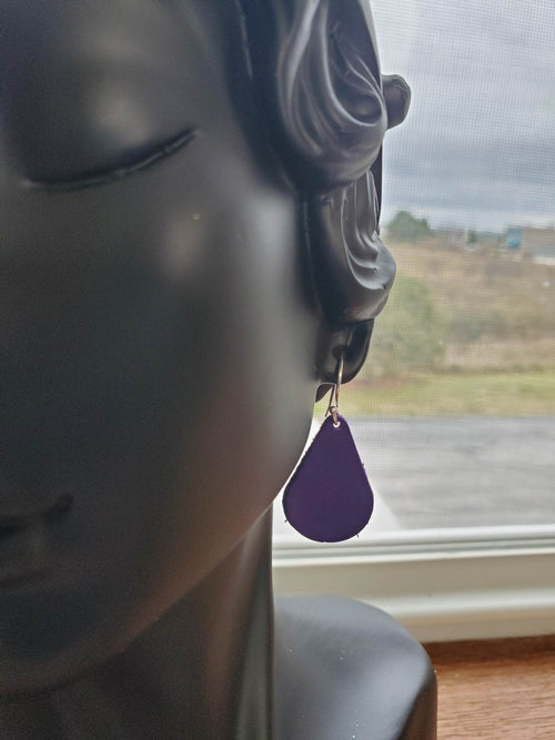 Purple teardrop leather earrings with silver fishhook, one hanging from ear
