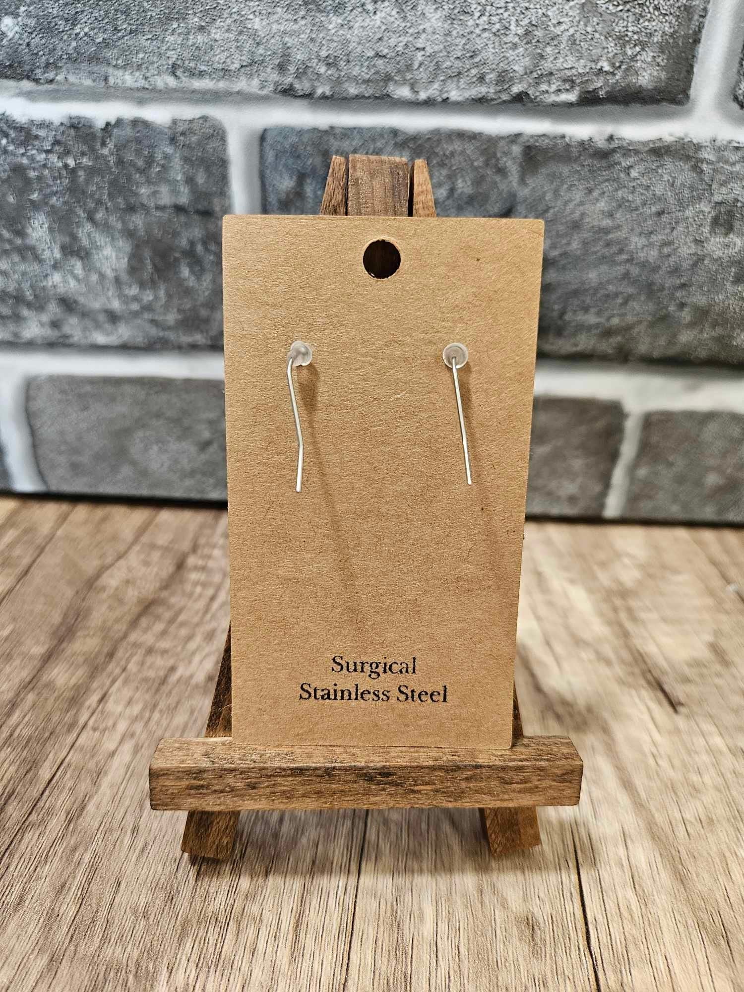 Surgical stainless steel hooks with purple teardrop leather earrings, on card