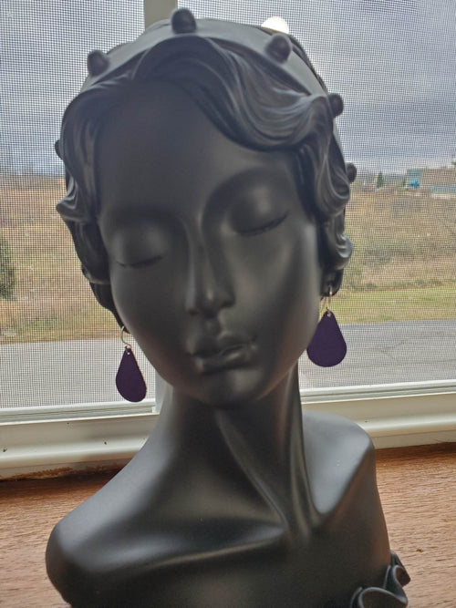 Pair of purple teardrop leather earrings with silver hooks, side view