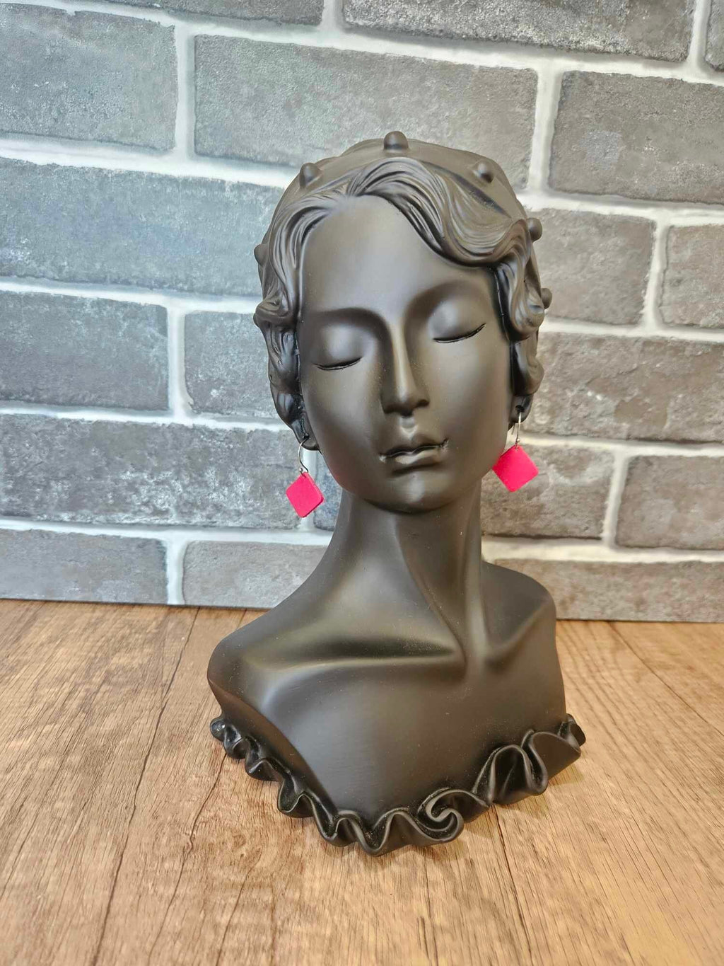 Red leather diamond earrings on silver hooks on a head mannequin bust, side view
