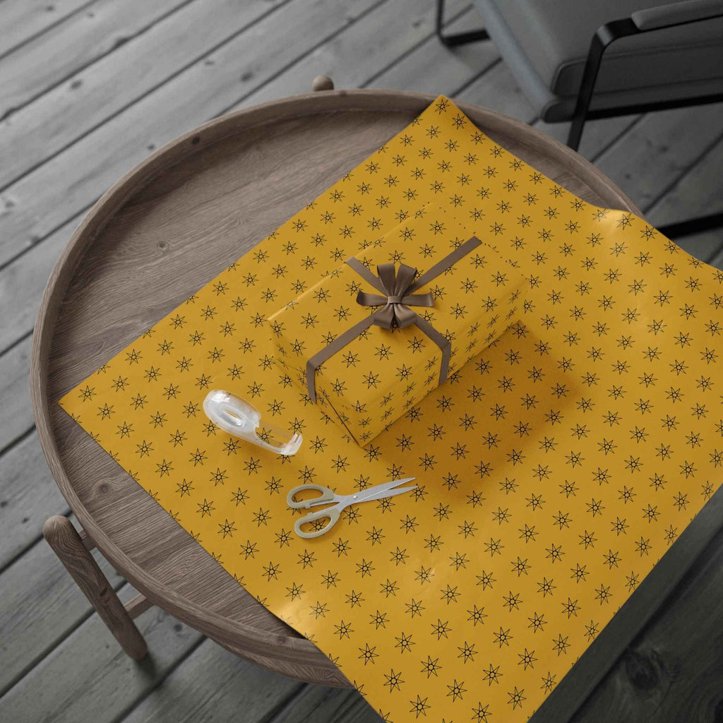 Yellow wrapping paper roll with seven-point star pattern, gift bow and ribbon shown