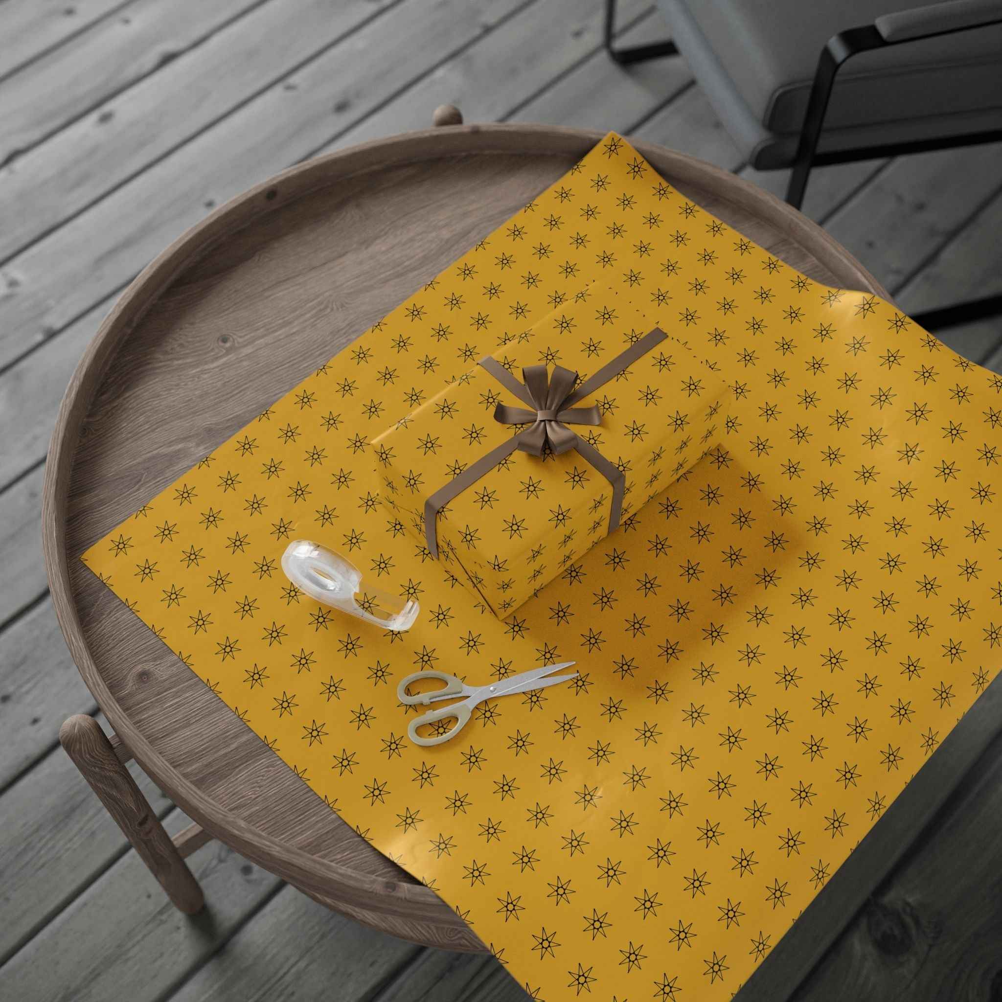Yellow wrapping paper roll with seven-point star pattern, gift bow and ribbon shown